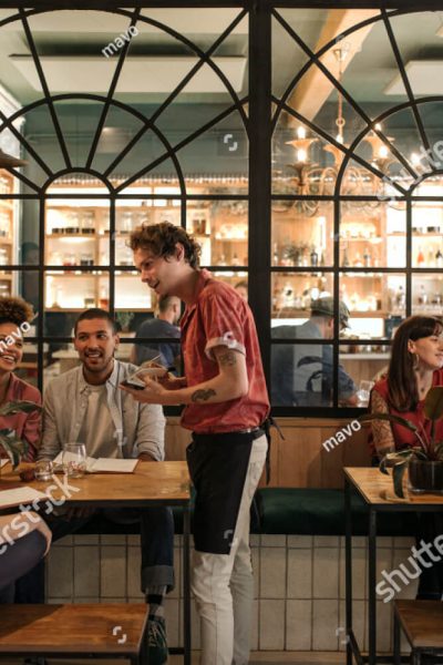 stock-photo-smiling-young-waiter-taking-orders-from-a-diverse-group-of-customers-sitting-together-at-a-1117119839